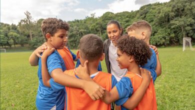 Cómo elegir el equipo de fútbol adecuado para tu hijo un grupo de niños jugadores de futbol abrazados reciben instrucciones de su entrenador